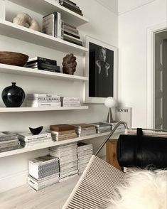 a living room filled with lots of white furniture and bookshelves on top of each other