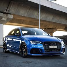 a blue car parked in front of a bridge