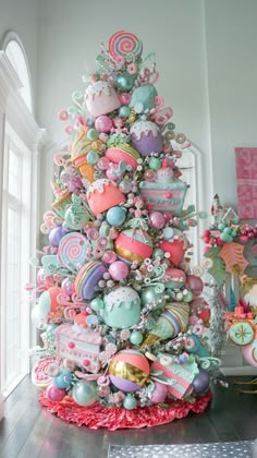 a decorated christmas tree in the corner of a room with pink and blue ornaments on it