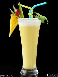 a tall glass filled with yellow liquid and topped with an umbrella shaped drink garnish