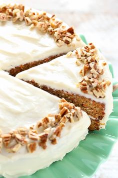 a cake with white frosting and pecans on top sitting on a green plate