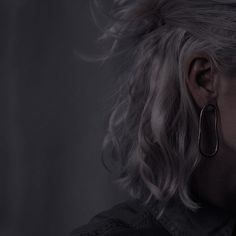 a woman with blonde hair and large hoop earrings on her ear looking off into the distance