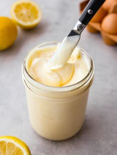 a glass jar filled with lemon custard next to an egg shell and sliced oranges