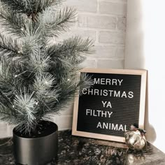 a christmas tree next to a sign that says merry christmas ya filthy animal