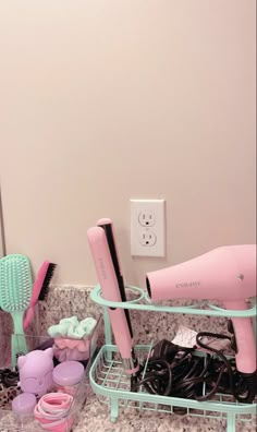 a pink hair dryer sitting on top of a counter next to a pile of hairbrushes