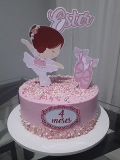 a pink cake with a ballerina figure on top and a name sign that says sister