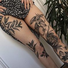 a woman's legs with tattoos on them sitting next to a potted plant