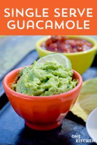 guacamole in a red bowl with lime wedges and salsa on the side