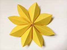 an origami flower made out of yellow paper on a white surface with no background