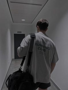 a man with a back pack walks down an empty hallway while holding onto a backpack