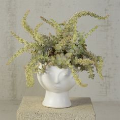 a white vase with some plants in it