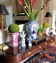 a table topped with vases filled with flowers next to a lamp on top of a rug