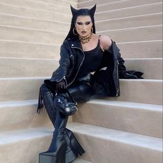 a woman sitting on some steps wearing cat ears and black leather pants with her hands in her pockets