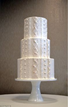 a three tiered white wedding cake sitting on top of a table