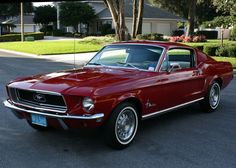 a red mustang is parked on the street