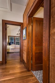 an open door leading to a bedroom with a bed in the background and hardwood floors