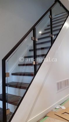 a stair case with glass railing and wood handrails in a house under construction