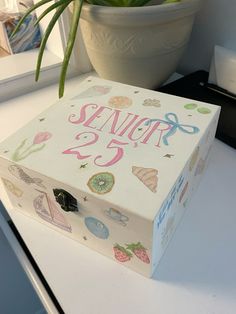 a white box sitting on top of a table next to a potted plant