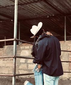 two people standing next to each other in front of a fence with a heart shaped hat on their head