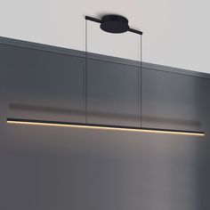 a modern light fixture hanging from the ceiling in a room with grey walls and flooring