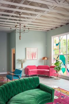 a living room with green couches and pink chairs