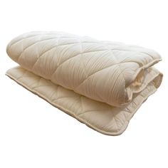 two blankets are folded on top of each other, one is white and the other is beige