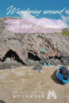 a blue kayak sitting on top of a sandy beach next to a rocky cliff