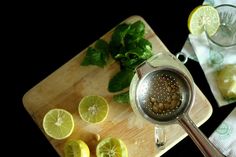 a cutting board topped with sliced lemons next to a glass filled with water and spices