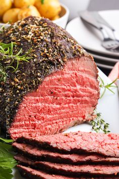 a large piece of meat on a plate with potatoes and parsley next to it