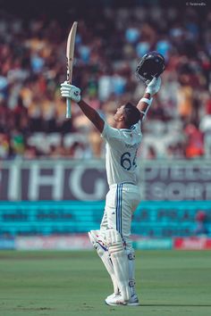 a cricket player holding his bat up in the air while standing on top of a field