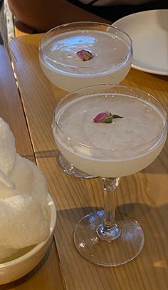 three glasses filled with drinks sitting on top of a wooden table