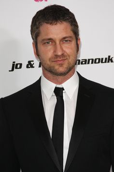 a man in a black suit and tie posing for the camera at an event with his hands in his pockets