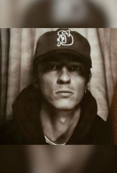 a black and white photo of a man wearing a baseball cap with the letter c on it