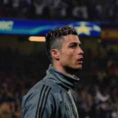 a man in a black jacket is looking off into the distance while standing on a soccer field