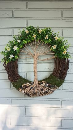 a wreath with a tree and flowers is hanging on the side of a brick building