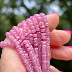 pink beads are held in the palm of a woman's hand