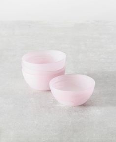 three pink bowls sitting on top of a cement floor next to each other and one is empty