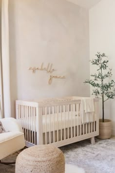 a baby's room with a white crib, chair and tree in the corner