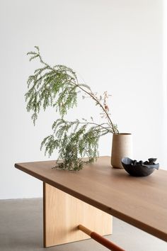 a wooden table topped with a vase filled with flowers and a plant sitting on top of it