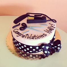 a birthday cake decorated with scissors, hairdryers and writing congratulations that is written on it