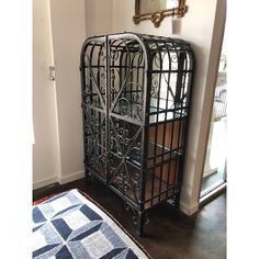 a black metal rack with baskets on top of it next to a rug and mirror