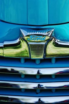 the front end of an old blue car with chrome hood ornament on it