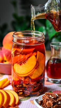 a glass jar filled with sliced peaches and pecans on top of a table