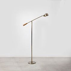 a floor lamp with a wooden stick on the base and a white wall in the background