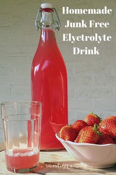 a bowl of strawberries next to a bottle of juice