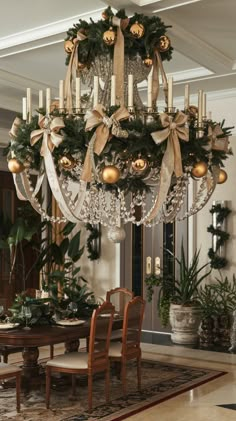 a chandelier hanging from the ceiling in a dining room with christmas decorations on it