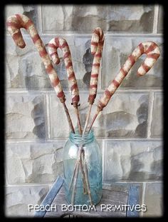 some candy canes are in a glass jar on a table next to a brick wall