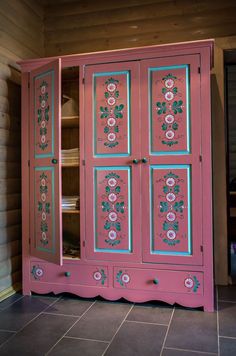 a pink armoire with flowers painted on the front and sides, in a room