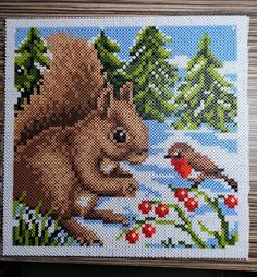 a cross stitch picture of a squirrel and a bird in the woods with flowers, grass and berries