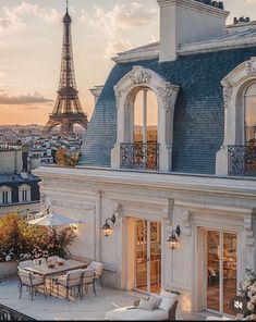 the eiffel tower is seen in the distance from an apartment balcony with tables and chairs